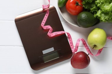 Elektronik mutfak ölçeği, mezura ve beyaz ahşap masa üzerindeki ürünler, düz yatak. Diyet
