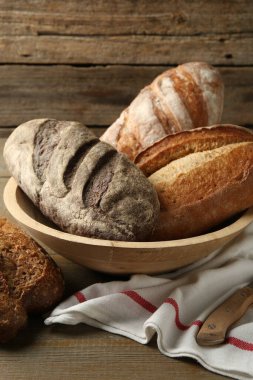 Tahta masada farklı somunlar taze ekmek ve bıçak.