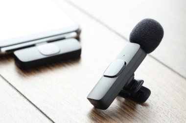 Lavalier mikrofon ve ahşap masada kablosuz alıcısı olan akıllı telefon.