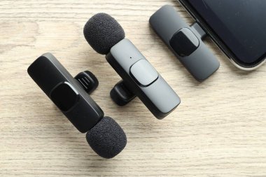 Lavalier mikrofonlar ve ahşap masada kablosuz alıcısı olan akıllı telefon.