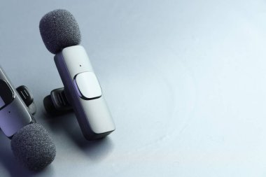 Açık gri arka planda Lavalier mikrofonları, yakın plan. Metin için boşluk