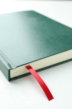 Beyaz masa üzerinde kırmızı kurdele yer imi olan kitap, yakın plan