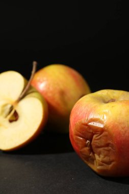 Siyah arkaplanda kesilmiş çürük elmalar, yakın plan.