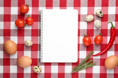 Boş tarif kitabı ve kareli masa örtüsü üzerindeki ürünler, düz konum