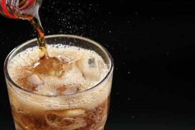 Siyah arka planda ferahlatıcı kolayı cama dökmek, yakın plan. Metin için boşluk