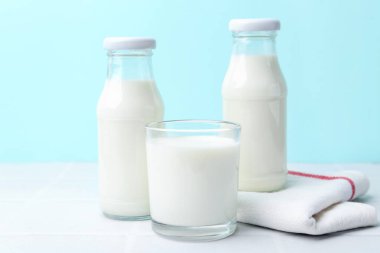 Açık mavi arka planda beyaz masada taze süt