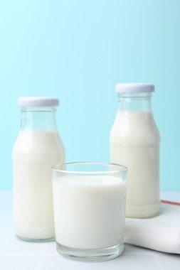 Açık mavi arka planda beyaz masada taze süt