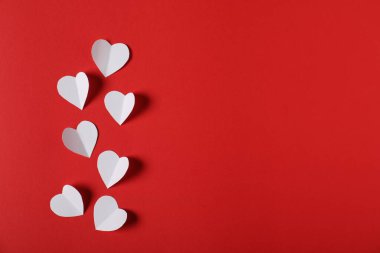 Kırmızı arka planda bir sürü kağıt kalp var. Metin için boşluk