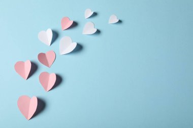 Açık mavi arka planda bir sürü kağıt kalp, düz yatış. Metin için boşluk