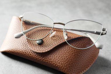 Gri masada şık gözlükleri olan bir çanta, yakın plan.