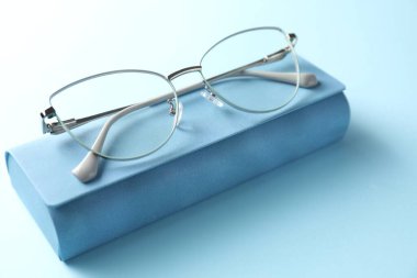 Açık mavi arka planda şık gözlüklü çanta, yakın plan