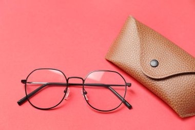 Kırmızı arka planda şık gözlüklü çanta, düz yatış