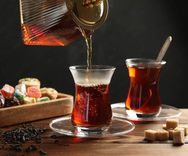 Tahta masada cam fincana Türk çayı dökülüyor, yakın plan.