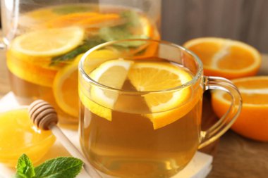 Cam fincanda aromatik meyve çayı, portakal, limon, bal ve nane. Masada, yakın plan.