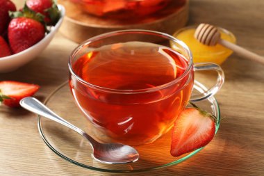 Çilekli Aromatik meyve çayı ve ahşap masada bal, yakın plan.