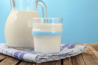 Açık mavi arka planda, ahşap masada taze süt, yakın plan.