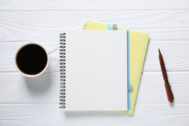 Kalem, defterler, renkli çıkartmalar ve beyaz ahşap masa üzerinde kahve, düz uzanmış.