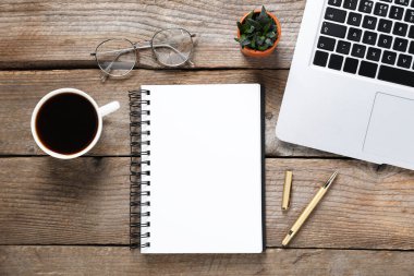 Kalem, açık defter, gözlük, çiçek dekoru, sehpada kahve ve dizüstü bilgisayar.