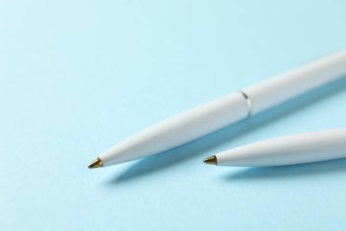 Açık mavi arkaplanda şık kalemler, yakın plan