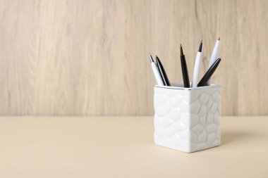 Tahta arka planda, bej masadaki tükenmez kalemler. Metin için boşluk