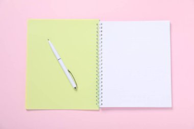 Kalem ve açık defter pembe arkaplan, üst görünüm