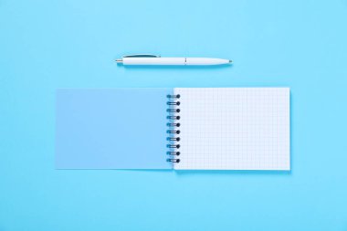 Açık mavi arkaplan üzerine açık kalem ve defter, düz yatıyordu