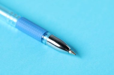 Açık mavi arka planda bir tükenmez kalem, makro görüş. Metin için boşluk