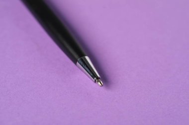 Mor arka planda şık bir kalem, makro görünüm. Metin için boşluk