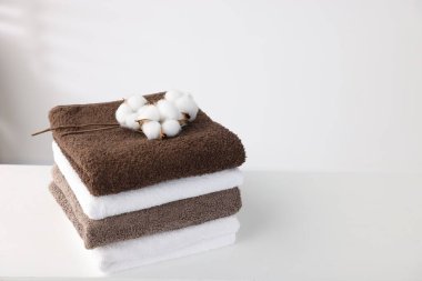 Beyaz masada bir yığın temiz havlu ve pamuk çiçeği. Metin için boşluk