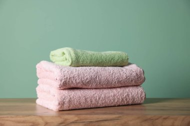 Ahşap masanın üzerine yığılmış temiz havlular yeşil arka plana karşı, yakın plan