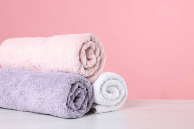 Açık mermer masa üzerindeki temiz havlular pembe arka plana karşı, yakın plan. Metin için boşluk