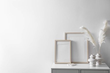Beyaz duvarın yanındaki dolapta boş resim çerçeveleri ve şık ev dekorasyonu, metin için boşluk