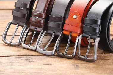 Ahşap masada birçok farklı deri kemer, yakın plan.