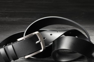 Ahşap masada siyah bir deri kemer, yakın plan.