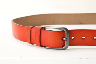 Beyaz masada bir turuncu deri kemer, yakın plan.