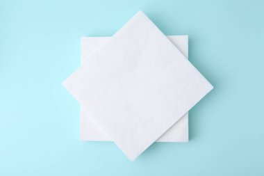 Açık mavi arkaplanda tek kullanımlık kağıt mendil yığını, üst görünüm