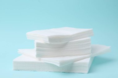 Açık mavi arkaplanda tek kullanımlık kağıt mendil yığını, yakın plan