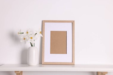 Vazodaki güzel nergisler ve evdeki beyaz masanın üzerindeki resim çerçevesi.