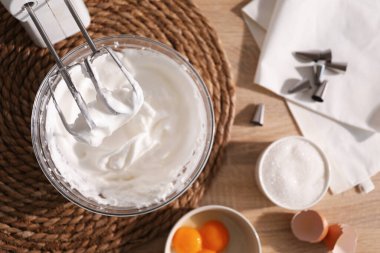 Çırpılmış çırpılmış çırpılmış kremalı el çırpıcısı, masada malzemeler, düz uzanmış.