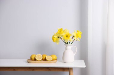 Vazodaki güzel nergisler ve beyaz masadaki limonlar.