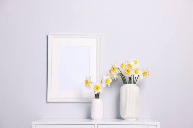 Dolaptaki vazolarda güzel nergisler ve evdeki resim çerçeveleri.