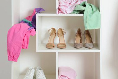 Farklı ayakkabı ve giysilere sahip raf ünitesi. Ayakkabı deposu