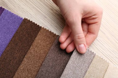 Ahşap masada farklı kumaşlardan örnekler taşıyan bir kadın, yakın plan.