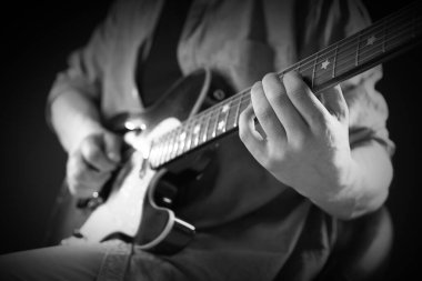 Karanlıkta gitar çalan adam, yakın plan. Siyah ve beyaz etkisi