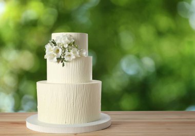 Dışarıdaki ahşap masada çiçeklerle süslenmiş güzel bir düğün pastası. Metin için boşluk