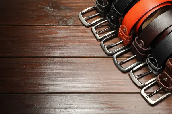 Ahşap masada birçok deri kemer var, manzaranın üstünde. Metin için boşluk