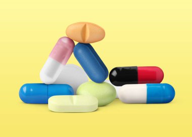 Sarı arka planda farklı antibiyotik hapları.