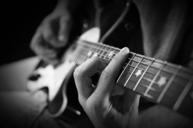 Karanlıkta gitar çalan adam, yakın plan. Siyah ve beyaz etkisi