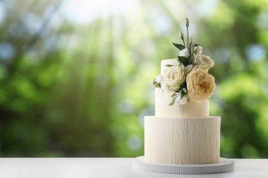 Dışarıdaki ahşap masada çiçeklerle süslenmiş güzel bir düğün pastası. Metin için boşluk