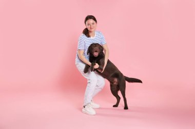 Hayvan eğitimi. Pembe arka planda sevimli köpeği olan bir kadın.